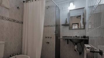 A bathroom with a shower, toilet, sink, and a mirror.