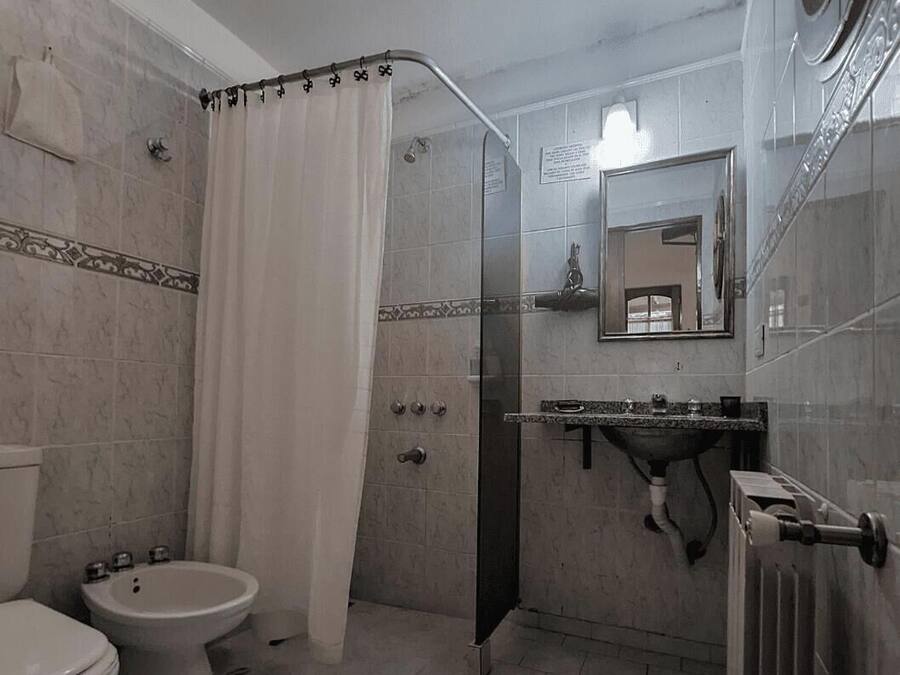 A bathroom with a shower, toilet, sink, and a mirror.