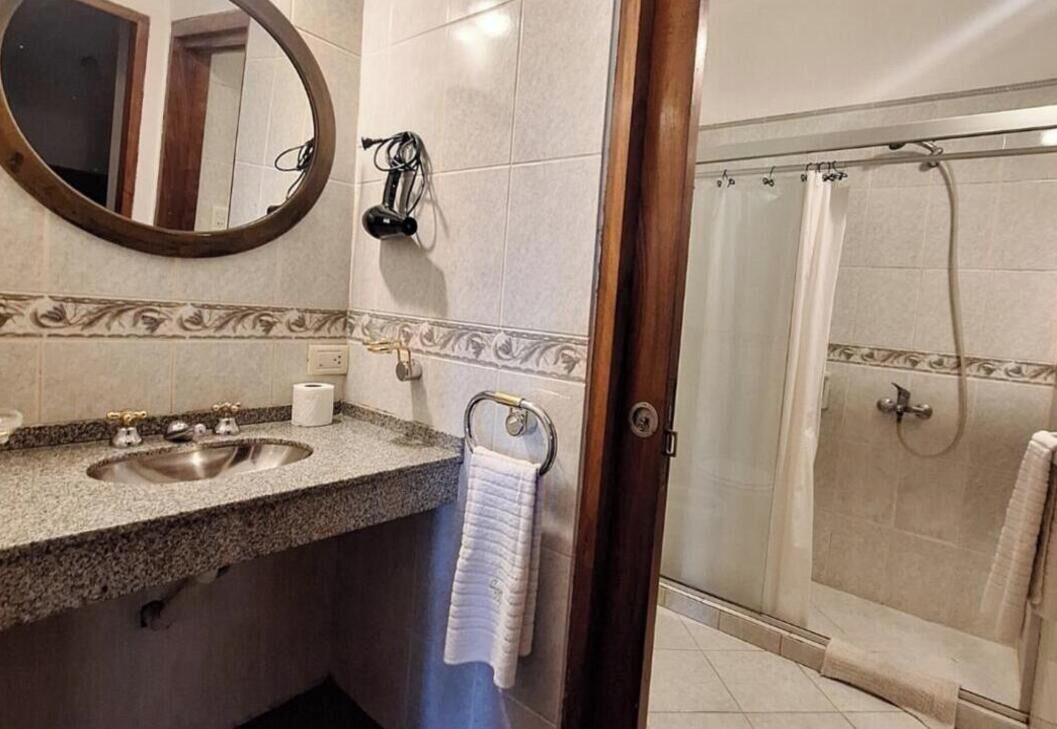 Une salle de bain équipée d’un lavabo, d’un miroir, d’un porte-serviettes et d’un espace douche.