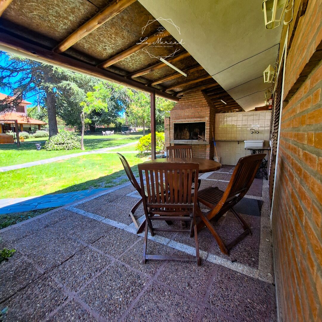 Une terrasse extérieure avec un four en briques, des chaises en bois et une table.