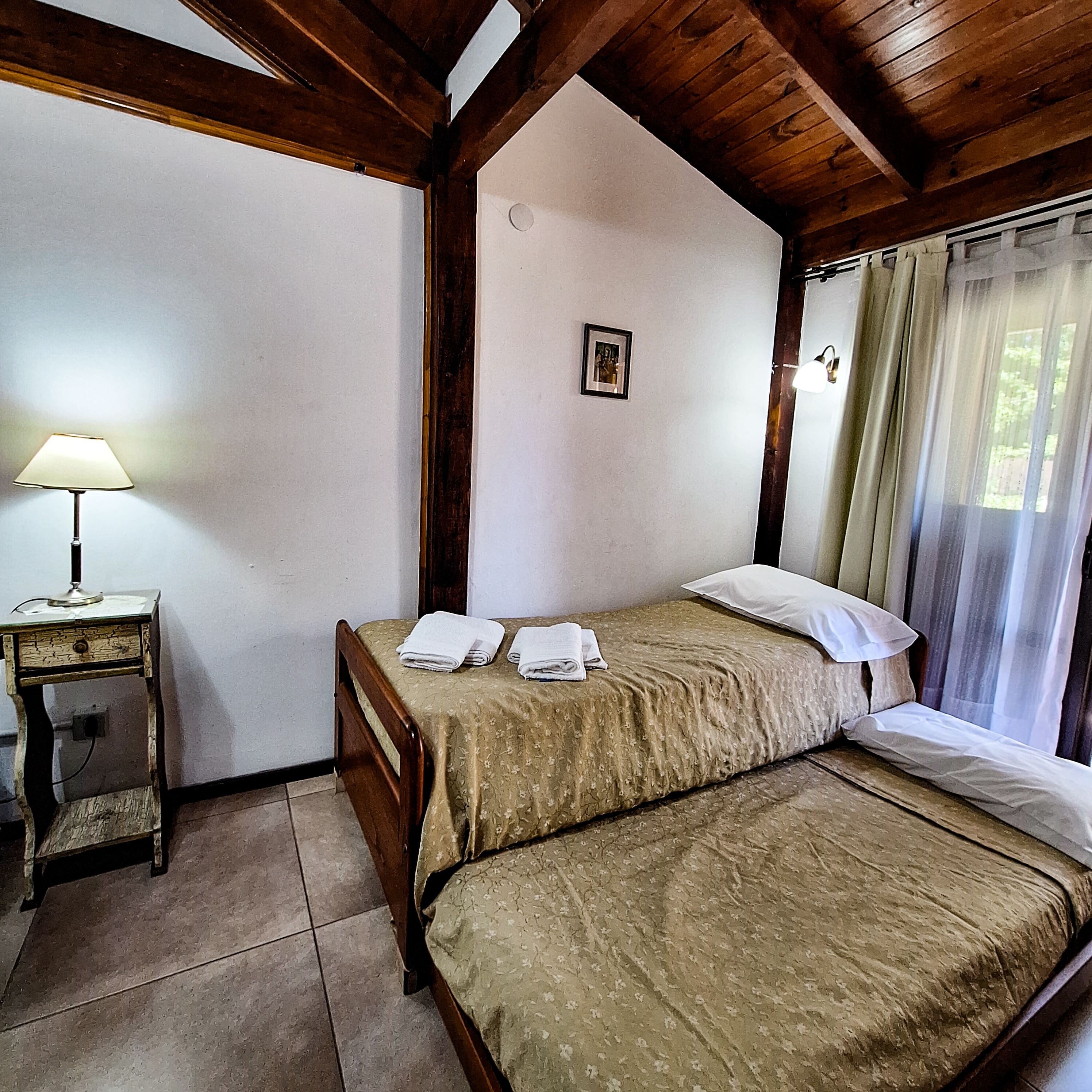 Une chambre avec un lit, une table de chevet avec une lampe et une fenêtre avec des rideaux.
