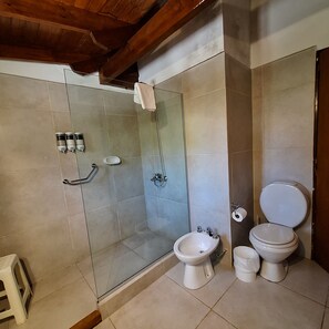Une salle de bain avec une douche à parois de verre, un bidet et des toilettes.