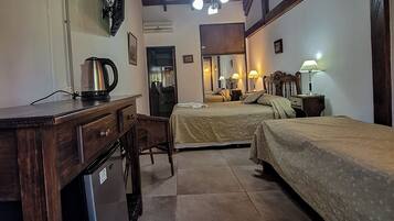 Habitación de hotel con kitchenette, dos camas, un espejo y un ventilador de techo.