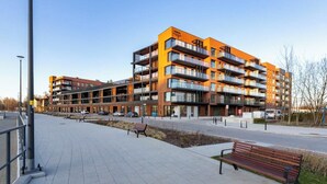A modern multi-story building with balconies, a paved walkway, and benches. - Nadmotławie Chic Apartment (Gdańsk)