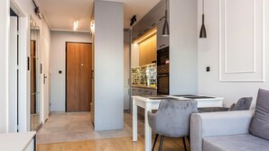A modern living room with a sofa, a dining table, and a kitchen area in the background. - Nadmotławie Chic Apartment (Gdańsk)