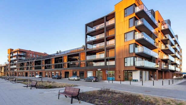 A modern multi-story building with balconies, a ground-level retail space, and a pedestrian walkway with benches. - Nadmotławie Chic Apartment (Gdańsk)