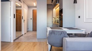 A modern apartment with a kitchen, dining area, and a hallway leading to a bedroom. - Nadmotławie Chic Apartment (Gdańsk)