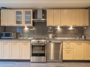 Una cocina moderna con gabinetes de madera, electrodomésticos de acero inoxidable y horno empotrado.