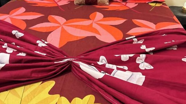 Un lit avec une couvre-lit à motifs floraux et deux oreillers.