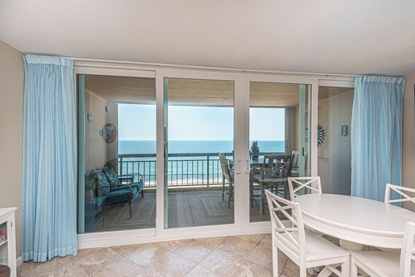 Una habitación con puerta de cristal corredera que da a un balcón con vista a la playa.