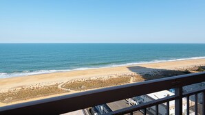 A beach view from a balcony with a clear sky, sandy beach, and a fence separating the beach from the adjacent area. - Fountainhead-Oceanfront Retreat w/ Expansive Private Balcony (Ocean City)