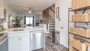 Une cuisine moderne équipée d’un lave-vaisselle, d’un évier et d’un plan de travail. Un escalier mène à un autre niveau.