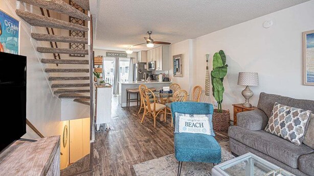 Un salon avec un escalier, un coin repas et une cuisine à l’arrière-plan.