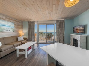 A living room with a sofa, a coffee table, a fireplace, a television, and a balcony with a view of the sea. - Roxanne Towers 303 (Myrtle Beach)