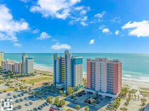 A coastal hotel with multiple high-rise buildings, a parking lot, and a beach view. - Roxanne Towers 303 (Myrtle Beach)