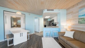 Een compacte woonruimte met een kitchenette, een eethoek en een zithoek met een bank.