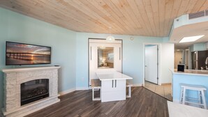 Een moderne woonkamer met een open haard, een aan de muur bevestigde televisie en een houten plafond.