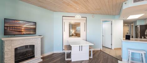 A modern living room with a fireplace, a TV mounted on the wall, and a wooden ceiling.