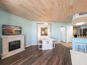 Ein modernes Wohnzimmer mit Kamin, einem an der Wand befestigten Fernseher und einer Holzbalkendecke.