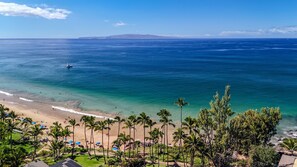 A beach with clear blue water, palm trees, and a distant mountain range. - Maui Vista 2310 - Fully Remodeled 1 BR/1 BA Close to Beach (Kihei)