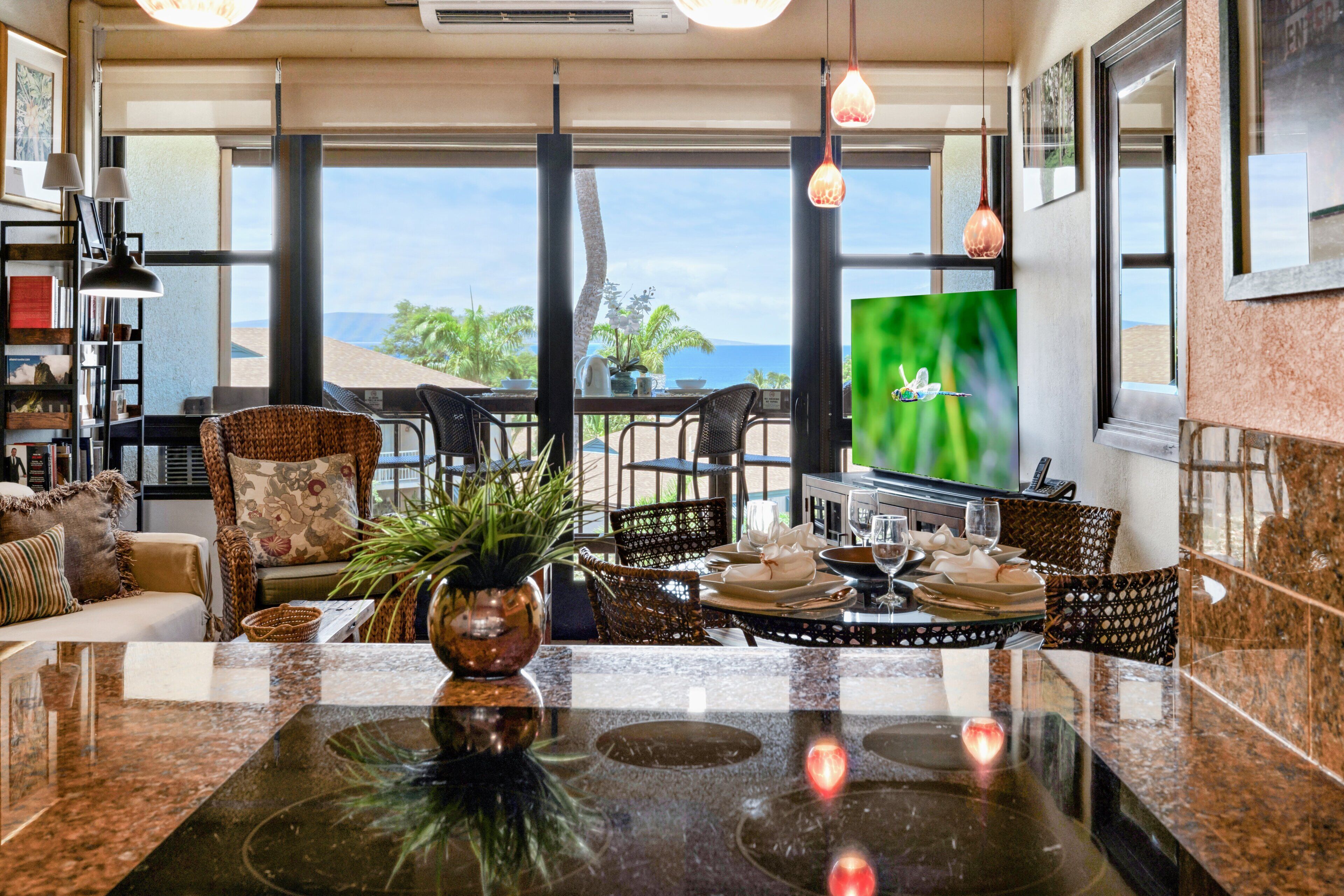 A spacious living area with a large window overlooking a scenic view, a dining table set with plates and glasses, and a television mounted on the wall.