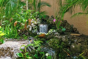 A small waterfall surrounded by lush greenery and rocks. - Maui Vista 3212 - Inviting 1 BR/1 BA near Beach (Kihei)