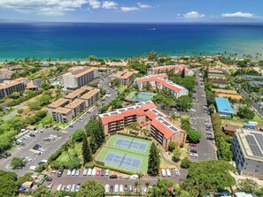 An aerial view of a coastal residential area with multiple buildings, a tennis court, and a view of the ocean. - Maui Vista 3212 - Inviting 1 BR/1 BA near Beach (Kihei)