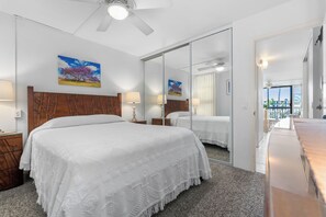 A hotel room with a large bed, a wooden headboard, a ceiling fan, and a large mirror. - Maui Vista 3212 - Inviting 1 BR/1 BA near Beach (Kihei)