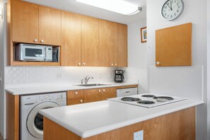 A modern kitchen with wooden cabinets, a microwave, a coffee maker, a dishwasher, and a stove. - Maui Vista 3212 - Inviting 1 BR/1 BA near Beach (Kihei)