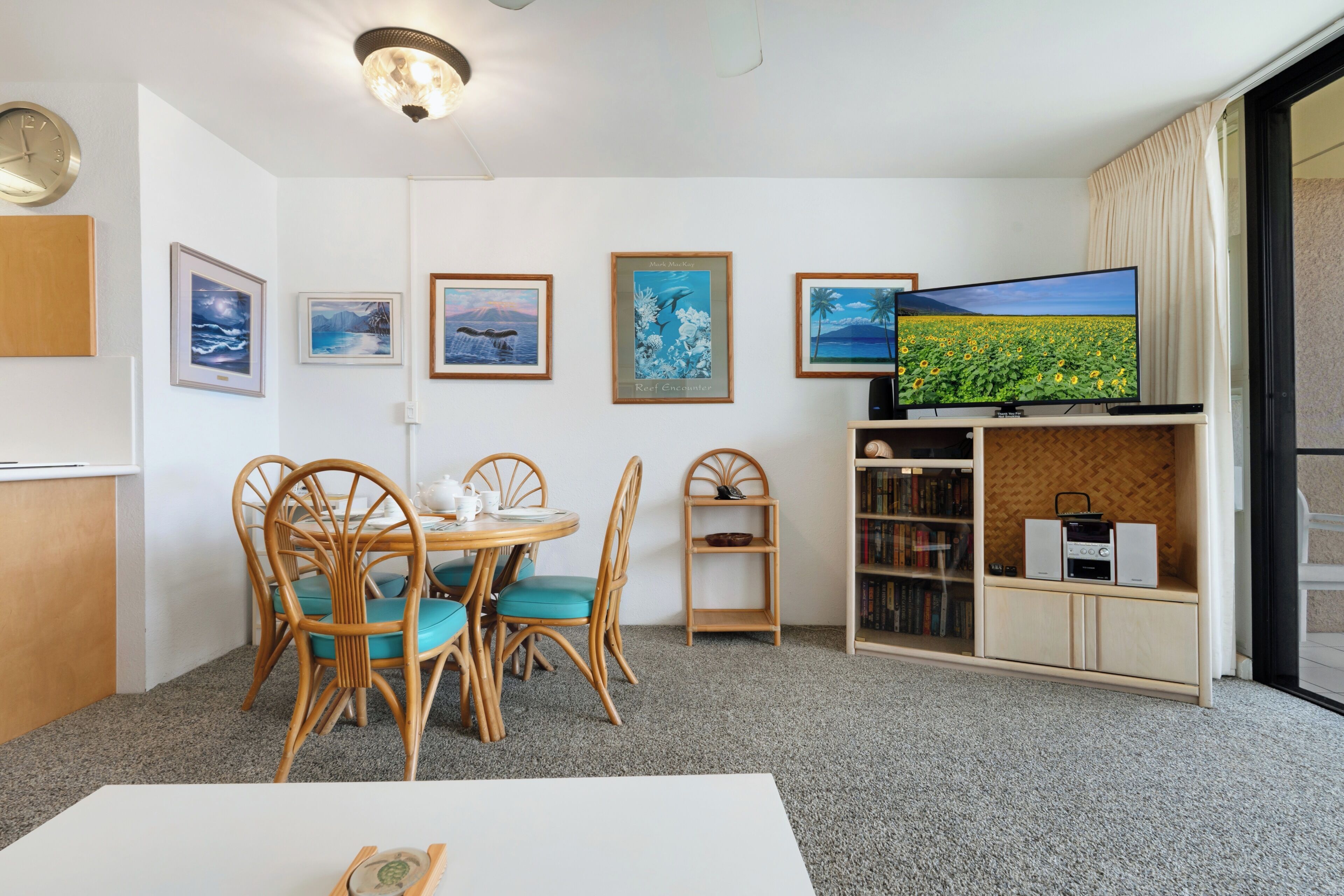 Una habitación con una mesa de comedor, sillas, un televisor y cuadros en la pared.