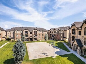 A multi-story residential building with a central courtyard, a basketball court, and a well-maintained lawn.