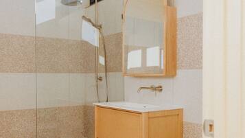 A bathroom with a glass shower enclosure, a wooden vanity, and a mirror above the sink.