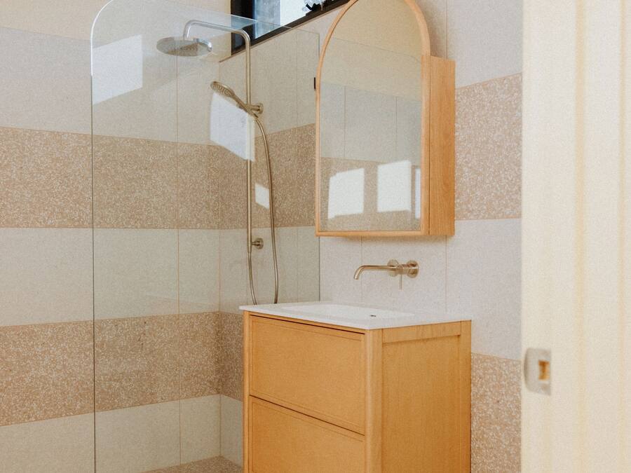 A bathroom with a glass shower enclosure, a wooden vanity, and a mirror above the sink.
