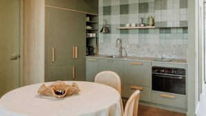 A compact kitchen with a round dining table, wooden chairs, and a built-in oven. - Hahndorf Farm Barn (Hahndorf)