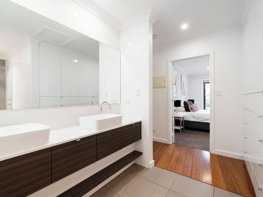 A modern bathroom with a large mirror, two sinks, and a dark wood vanity.