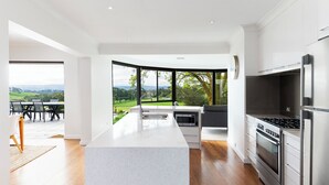 A modern kitchen with a large island, stainless steel appliances, and a view of a green landscape. - Hahndorf Farm Barn (Hahndorf)