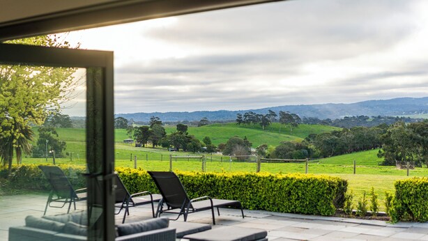 A patio with outdoor furniture overlooking a green landscape. - Hahndorf Farm Barn (Hahndorf)