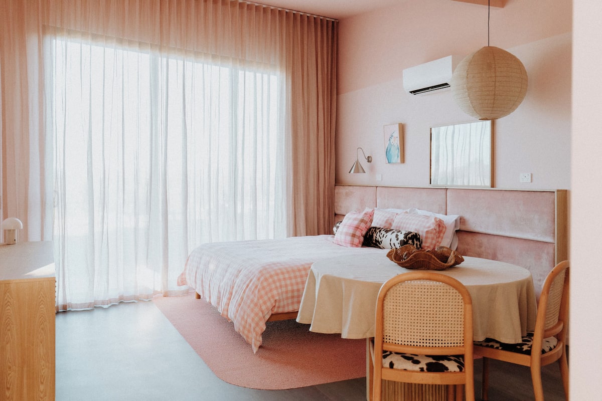 A bedroom with a bed, bedside table, and a round table with chairs.