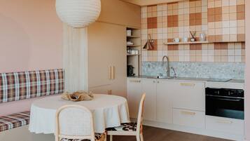 Una cocina moderna con una mesa de comedor redonda, dos sillas, un banco con cojín a cuadros y una lámpara colgante.