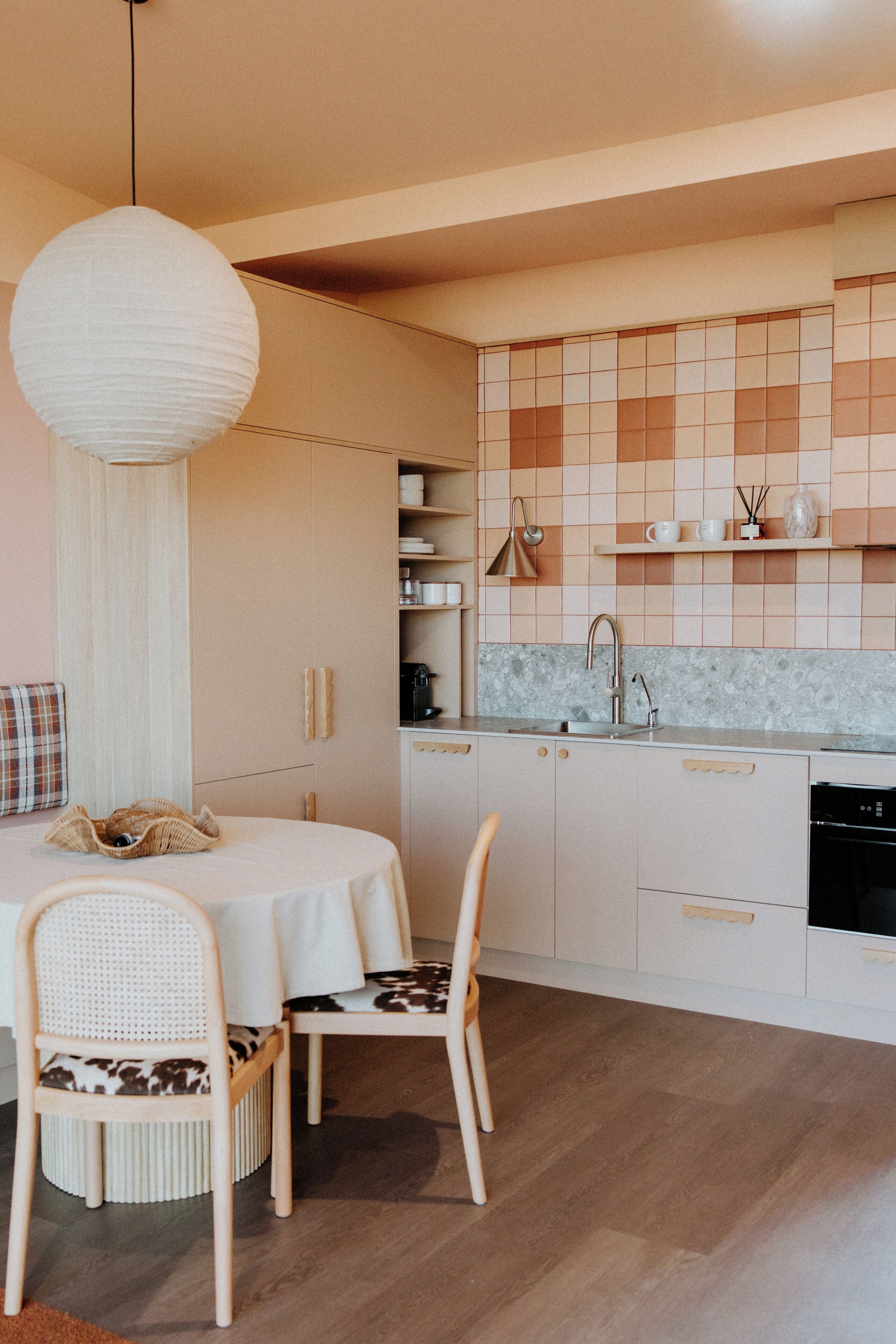 A modern kitchen with white cabinetry, a round dining table, and two chairs.