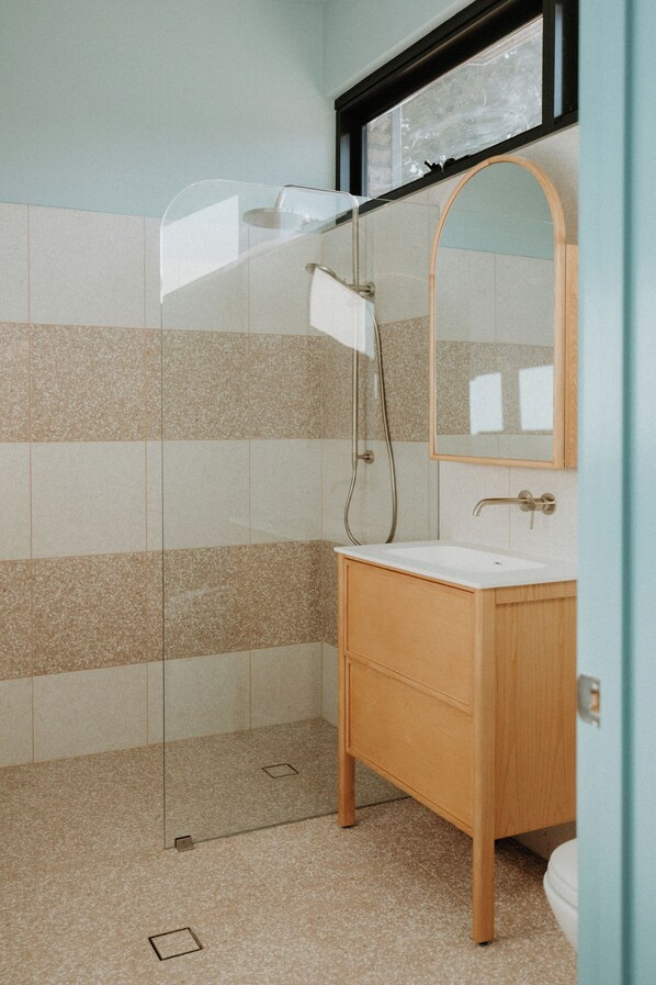 A bathroom with a glass shower enclosure, a wooden vanity, and a mirror above the sink. - Hahndorf Farm Barn (Hahndorf)
