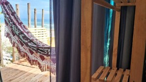Une pièce avec un banc en bois, un hamac et une vue sur la plage.