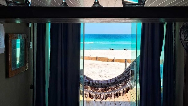 Une chambre avec un lit, une vue sur la plage et trois verres à vin fixés au plafond.