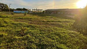 A grassy field with a building in the background. - PORTAL DA LAGOA AZUL INN IN NOBRES (Coqueiral)
