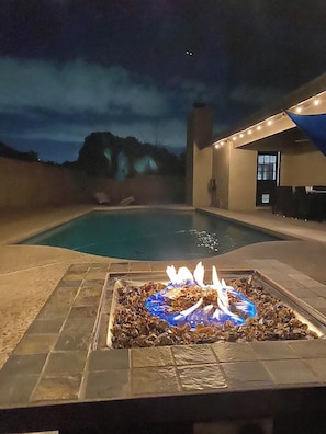 Una piscina con un elemento decorativo a forma di fuoco al centro, circondata da piastrelle in pietra.