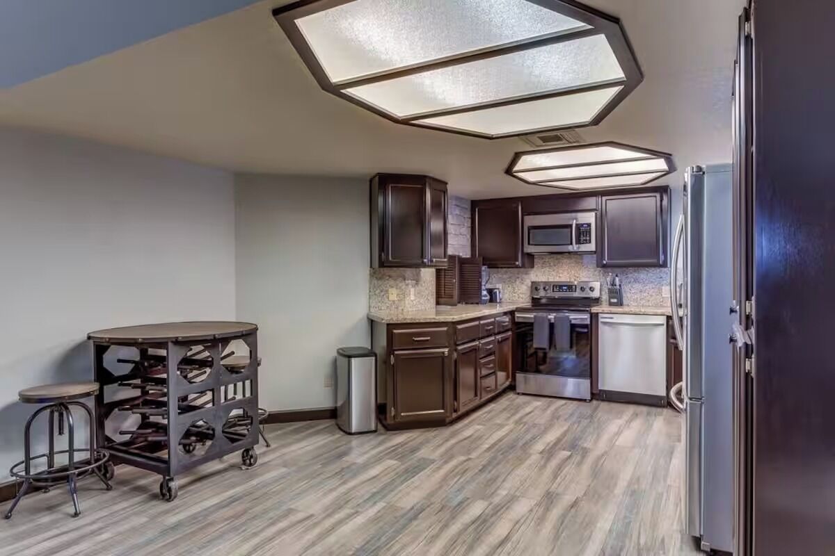 A modern kitchen with dark wooden cabinets, a stainless steel refrigerator, and a microwave.