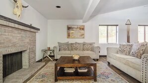 A living room with a fireplace, a sofa, a coffee table, and a painting on the wall.