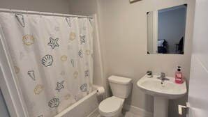 Ein Badezimmer mit Toilette, Waschbecken und Duschvorhang mit Muschelmotiv.