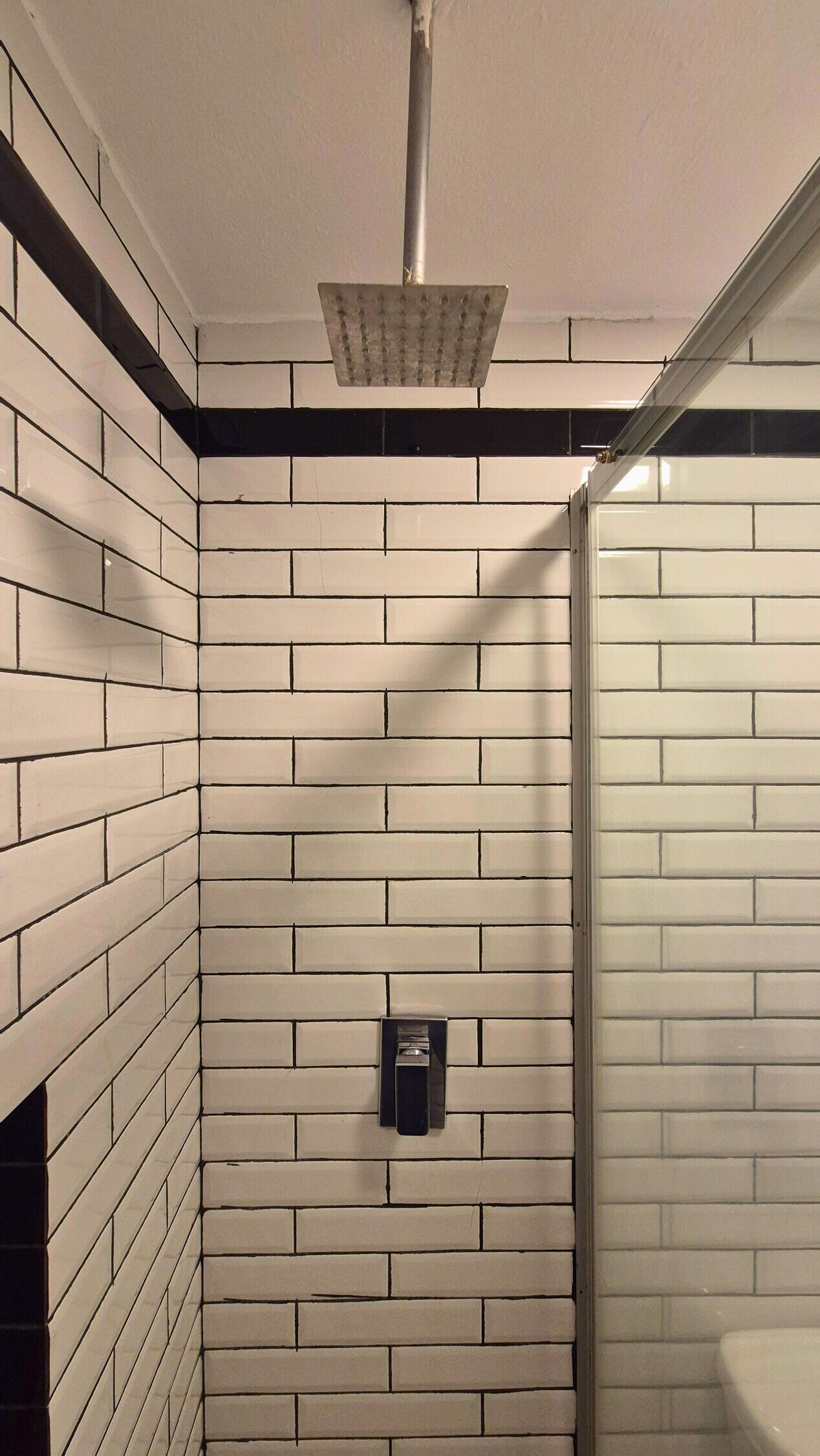 A bathroom with white subway tiles, a shower, and a towel rack.