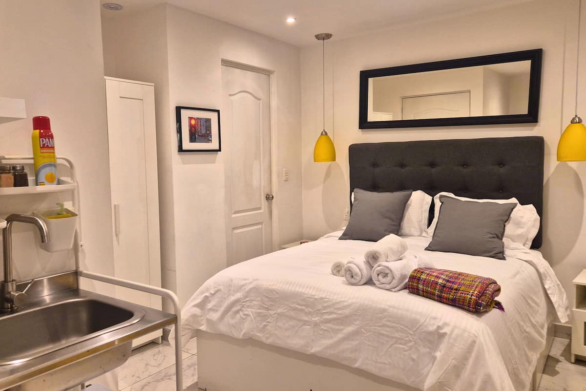 A hotel room with a bed, a bathroom with a sink, and a mirror.